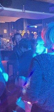 Bunte Lichter und Menschen, die in einer lebhaften Atmosphäre tanzen.